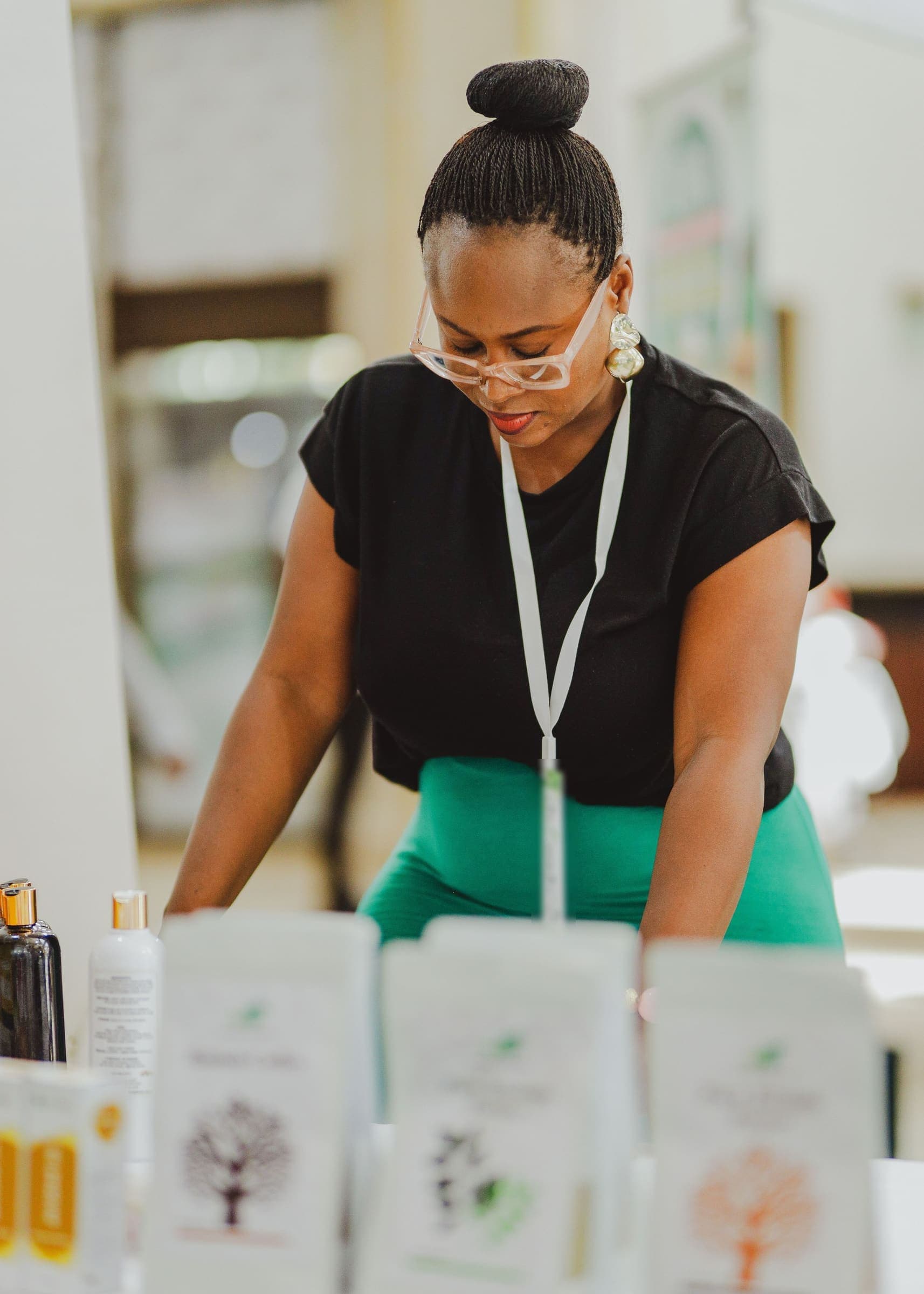 Une femme d’affaires portant un badge de délégué dispose des échantillons de produits sur une table d’exposition.